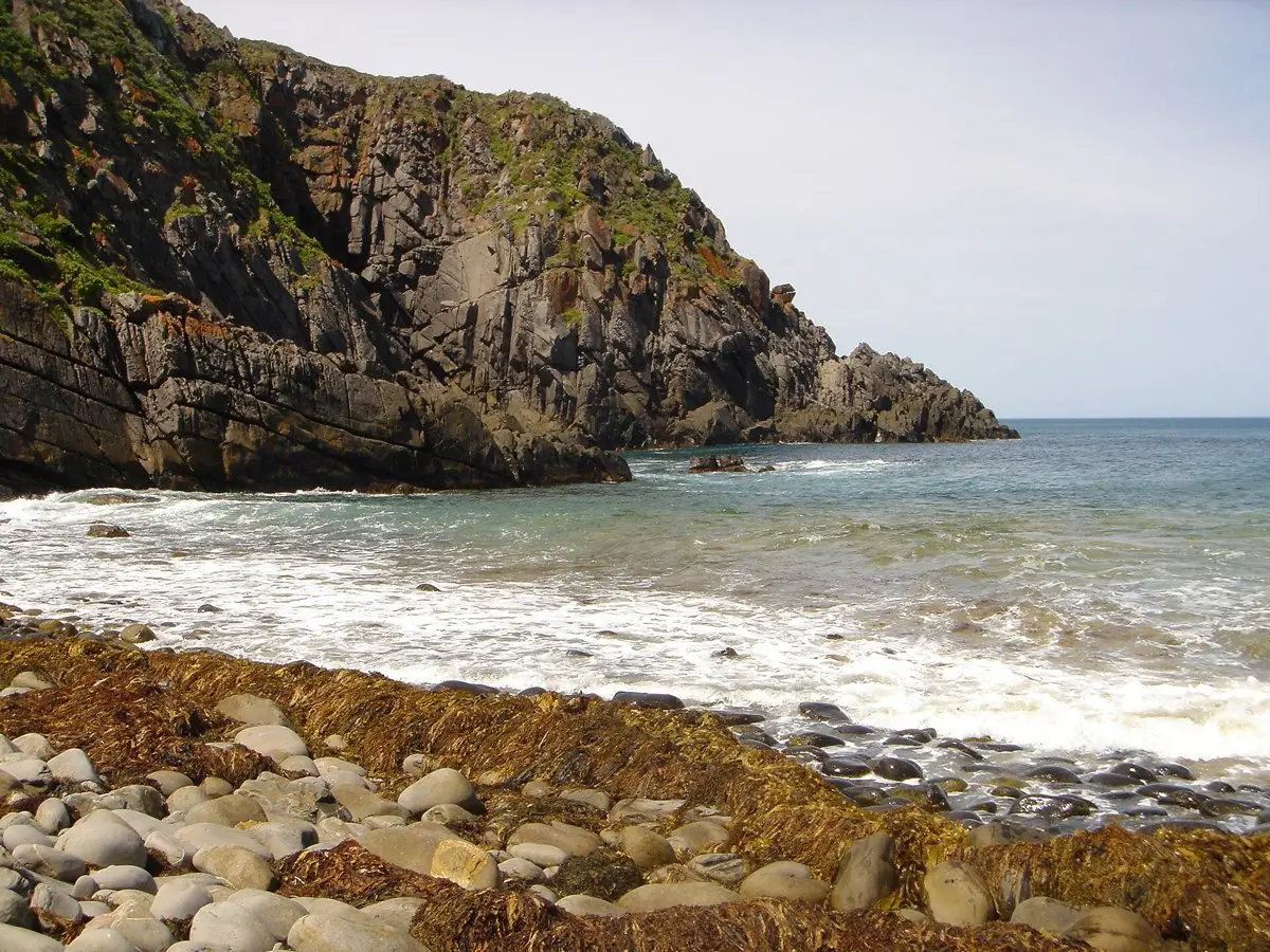 Rocky cliffs and a pebbly beach with waves at Deep Creek Conservation Park on the Fleurieu Peninsula